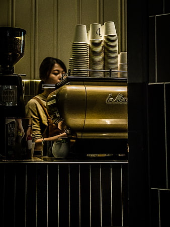 Barista working behind espresso machine in dim cafe