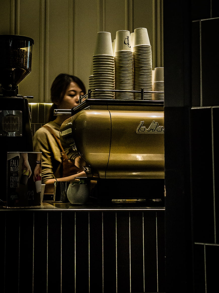 Barista working behind espresso machine in dim cafe
