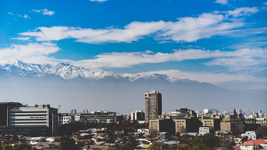 Cityscape with Snow-Capped Mountains and Blue Sky