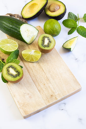 Fresh green fruits and vegetables on wooden cutting board