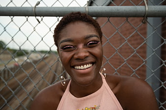Happy Black Woman Smiling by Chain Link Fence