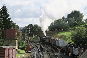 Vintage steam train emitting smoke at a railway station in Scotland