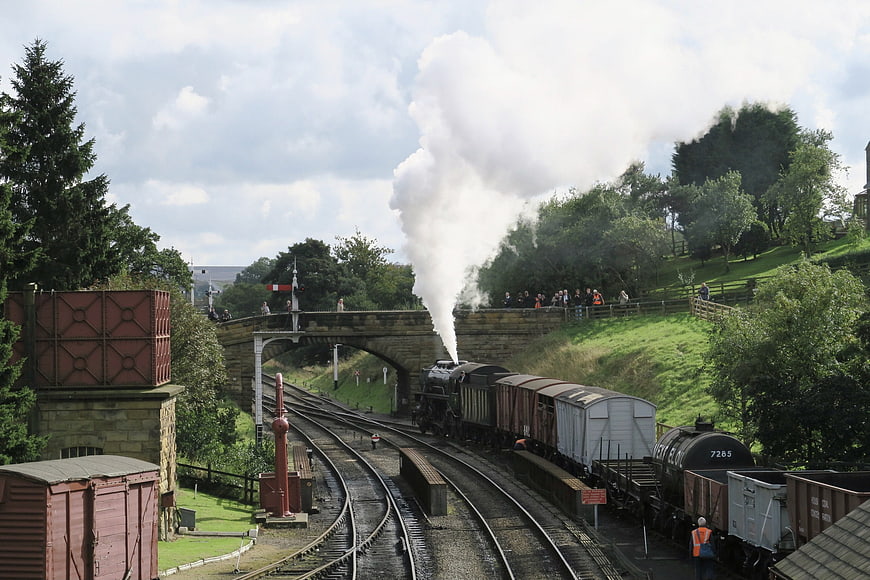 Vintage steam train emitting smoke at a railway station in Scotland