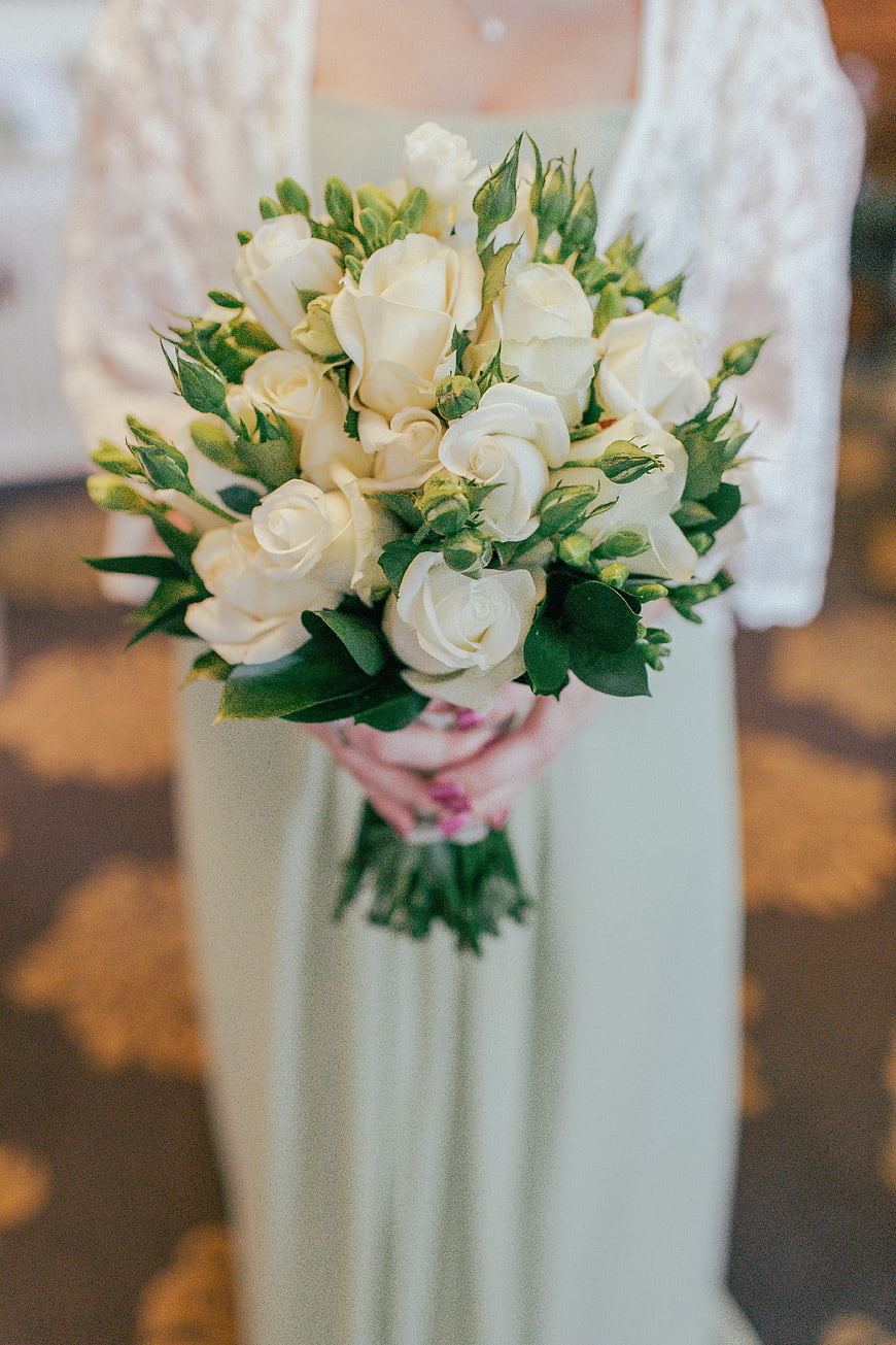 Bride holding white rose bouquet in wedding dress