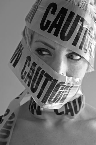 Woman's face wrapped in black and white caution tape