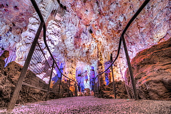Colorful illuminated cave interior with stalactites and walkway