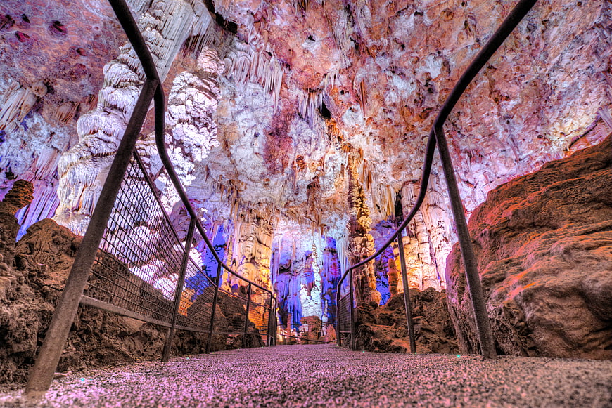 Colorful illuminated cave interior with stalactites and walkway