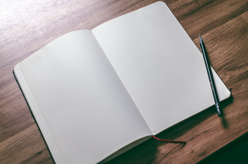 Open blank notebook with pencil on wooden desk