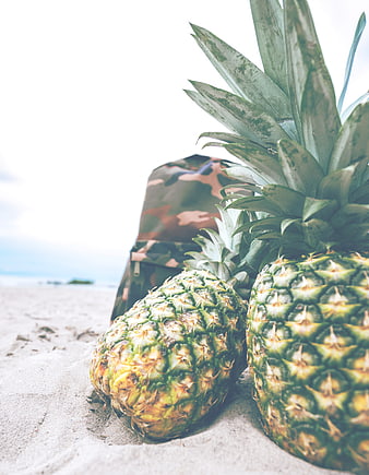 Fresh Pineapples on Sandy Beach with Camouflage Bag