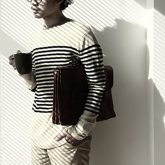 Man with coffee and leather bag in striped shadows