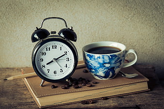 Vintage alarm clock and coffee cup on a book