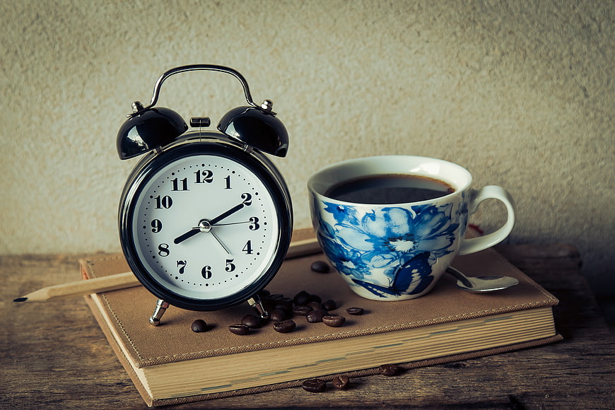 Vintage alarm clock and coffee cup on a book