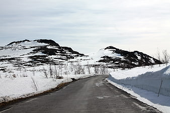 Winding asphalt road through snowy winter mountain landscape