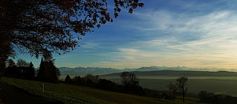 Panoramic autumn landscape with misty mountains and tree branches