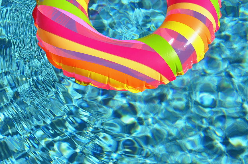 Colorful striped inflatable swim ring floating in clear blue pool water