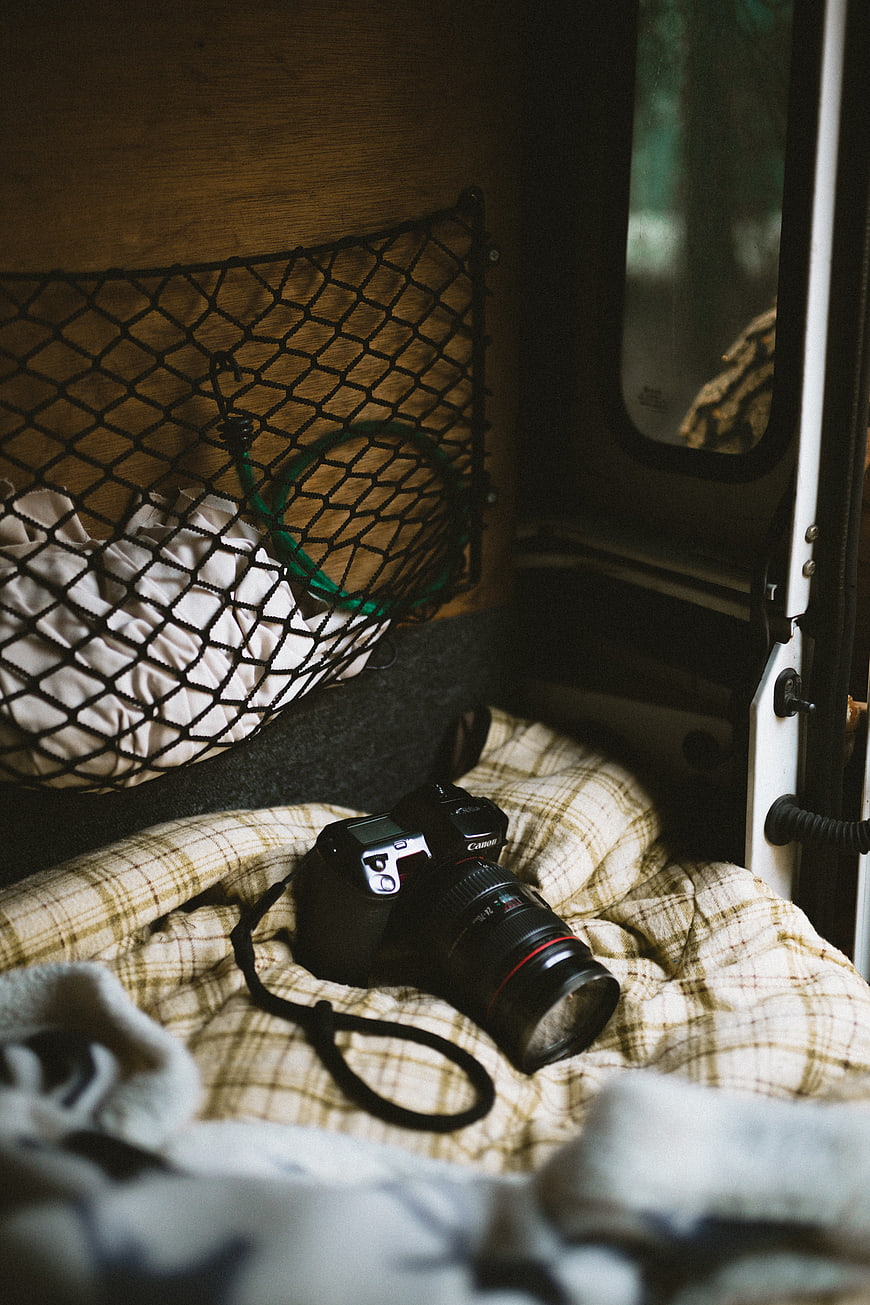 DSLR Camera on Plaid Blanket in Van Interior