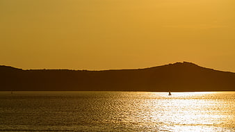 Silhouette of sailboat on golden sunset water