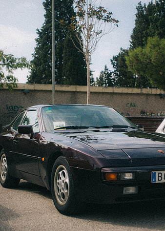 Vintage dark purple Porsche 944 parked on street