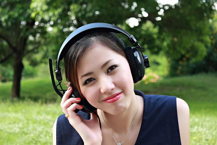 Young Woman Listening to Music with Headphones in Park