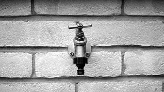 Black and white outdoor faucet on brick wall