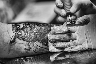 Close-up of tattoo artist inking an owl design on skin