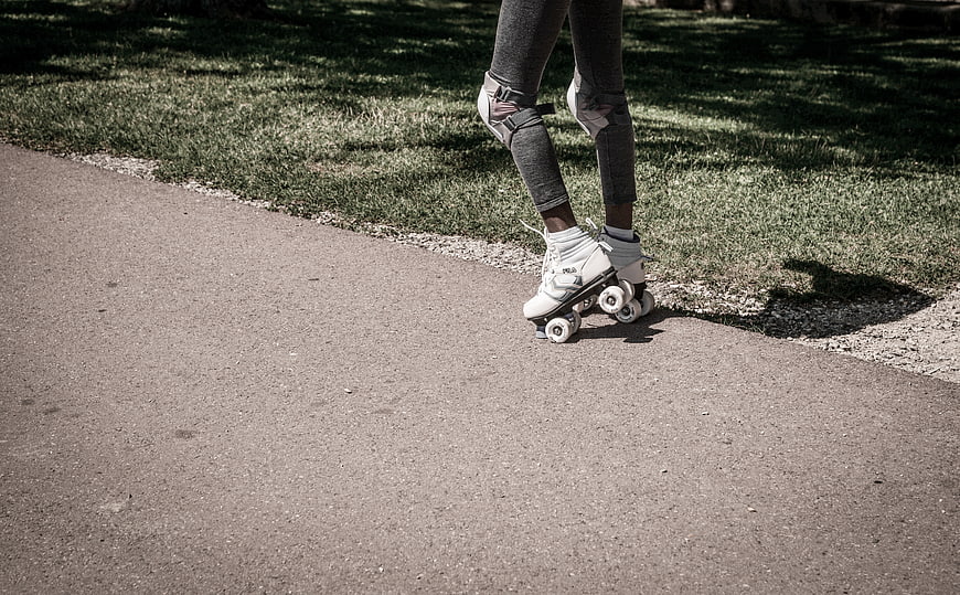 Close-up of legs roller skating on a paved path