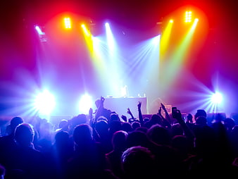 Energetic concert crowd with vibrant stage lights and DJ