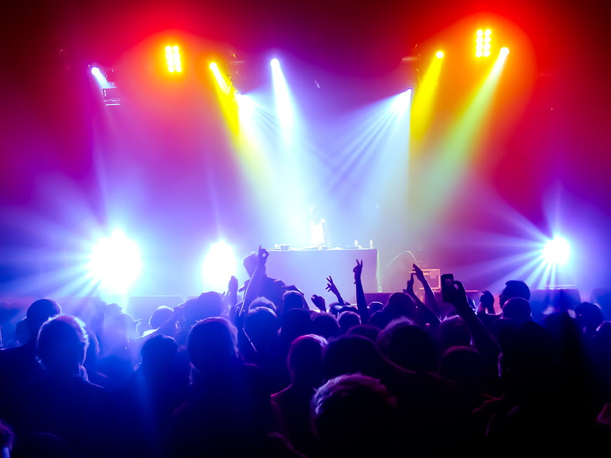 Energetic concert crowd with vibrant stage lights and DJ