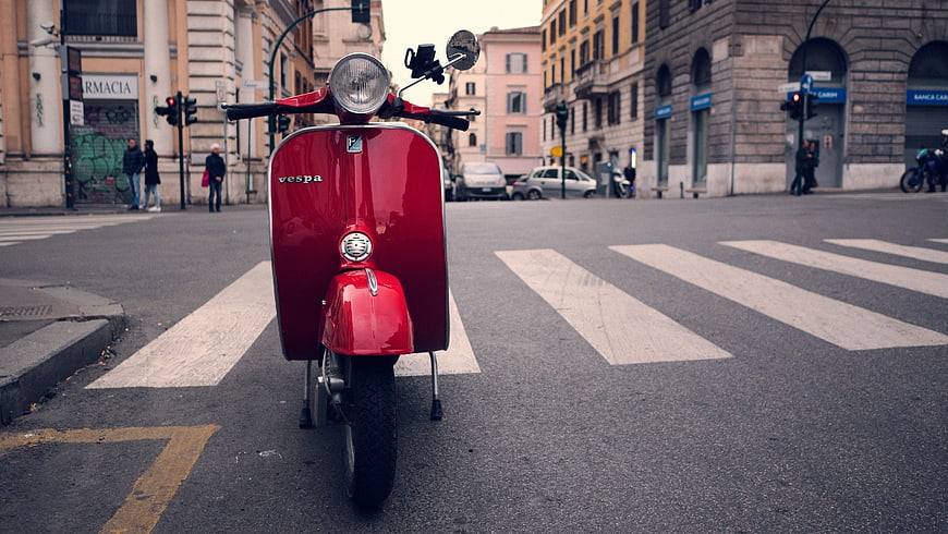Red Vespa Scooter on City Street Crosswalk