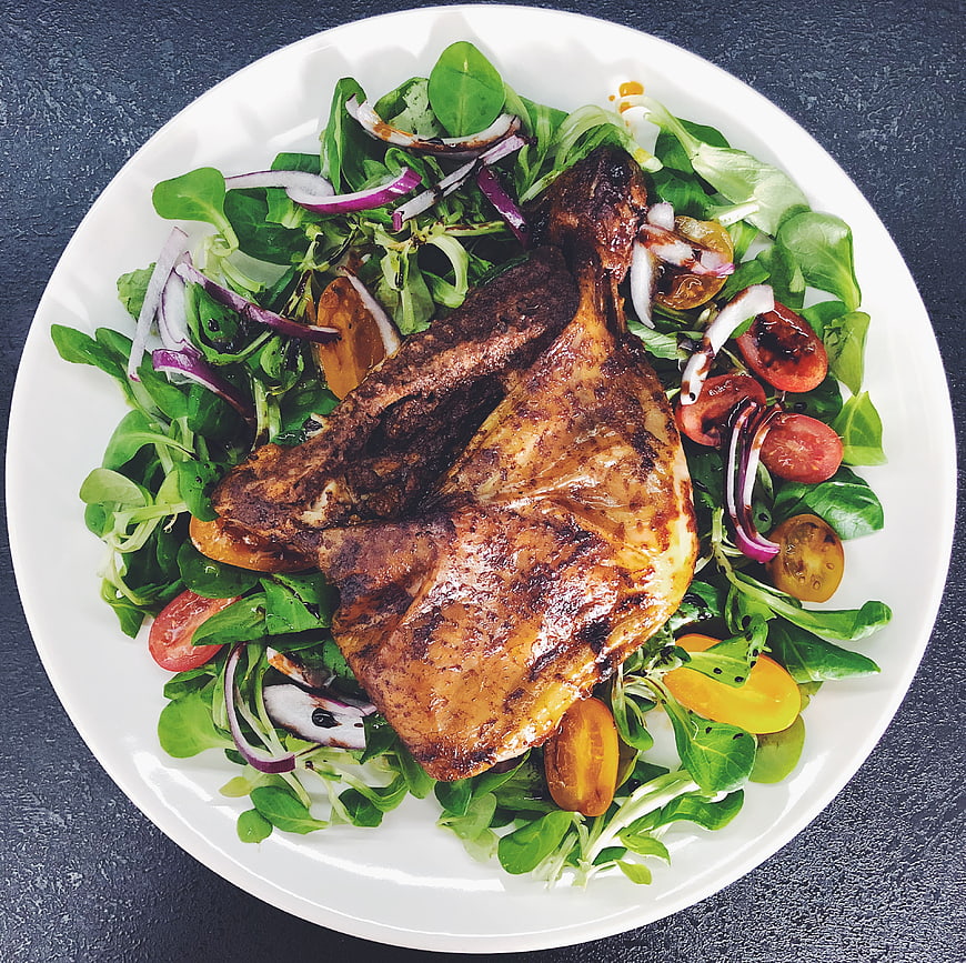 Overhead shot of grilled chicken breast on fresh salad