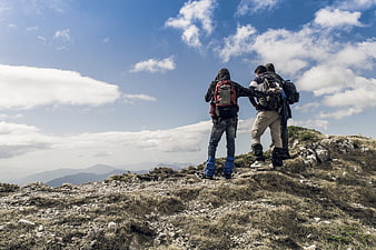 Hikers with backpacks standing on mountain ridge looking at view