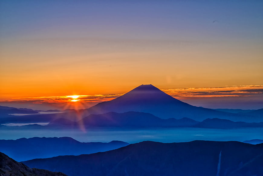 Sunrise over Mount Fuji with layered mountain silhouettes