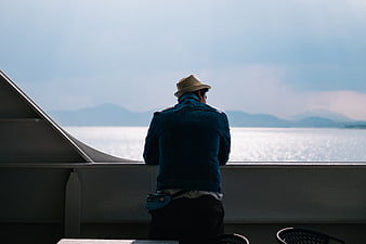 Man in hat looking out at ocean from ship deck
