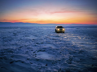 SUV Driving on Frozen Lake at Sunset
