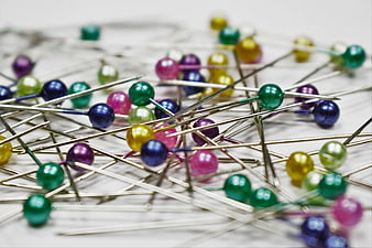 Scattered colorful sewing pins on white background