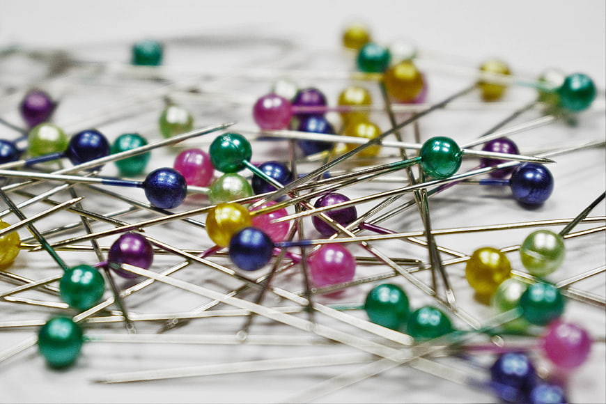 Scattered colorful sewing pins on white background