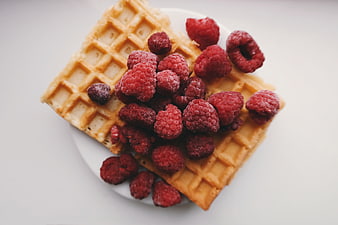 Overhead shot of waffles with frozen raspberries on white plate