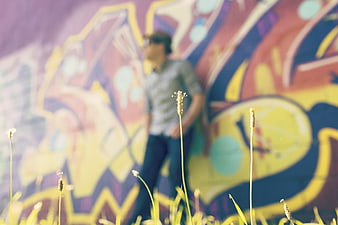 Blurred Man Standing in Front of Colorful Graffiti Mural