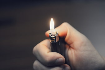 Close-up of hand holding lit lighter with flame