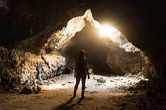 Woman Silhouette Exploring Dark Cave with Light