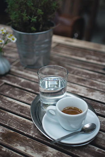 Espresso and water on rustic wooden table outdoors