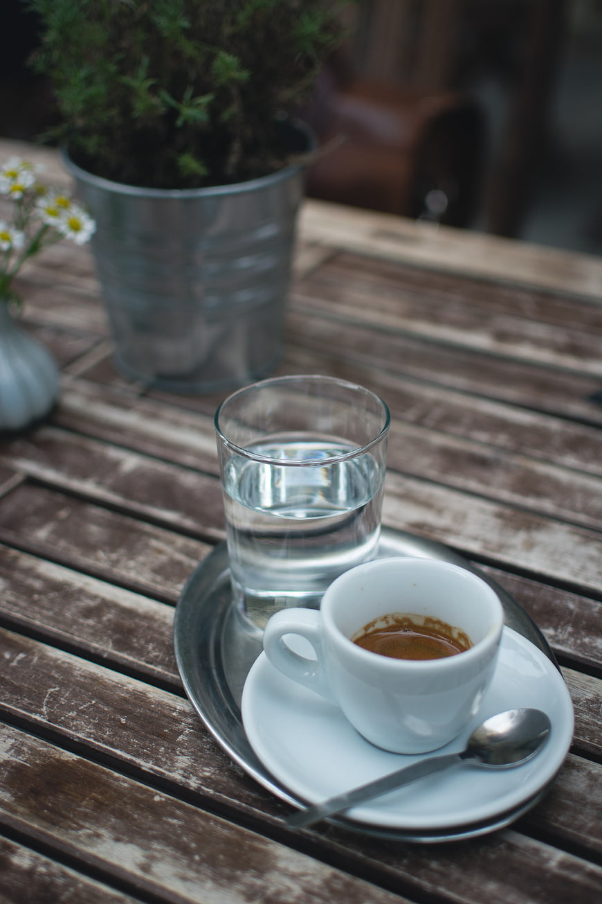 Espresso and water on rustic wooden table outdoors