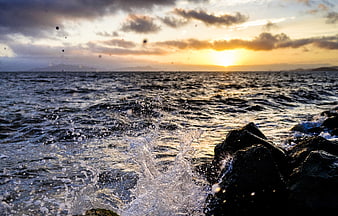 Dramatic Ocean Sunset with Splashing Waves on Rocks