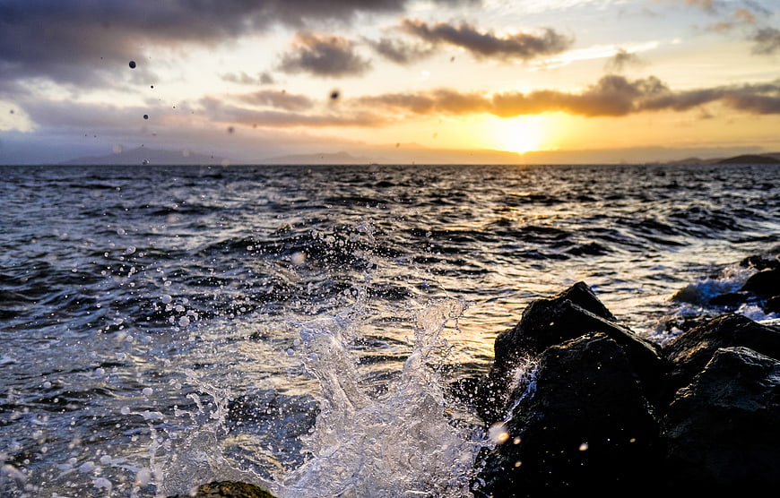 Dramatic Ocean Sunset with Splashing Waves on Rocks