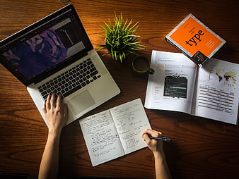 Top-Down View of Designer Workspace with Laptop, Sketchbook, and Books