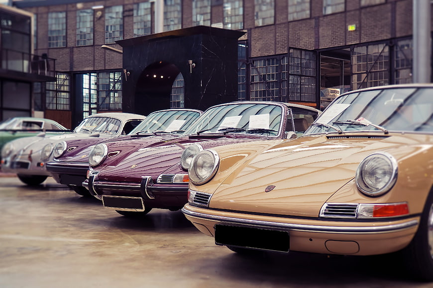 Row of vintage Porsche 911 classic cars parked in industrial courtyard