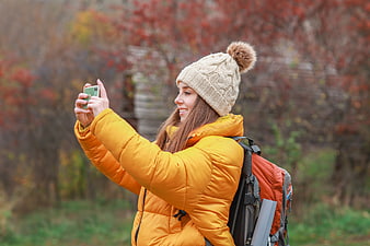 Woman in yellow jacket taking selfie in autumn forest