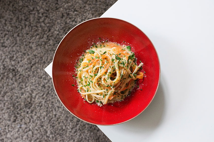 Overhead view of creamy spaghetti in a red bowl