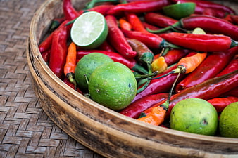 Fresh red chili peppers and limes in a wooden bowl