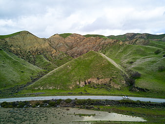 White truck driving on coastal highway through green hills